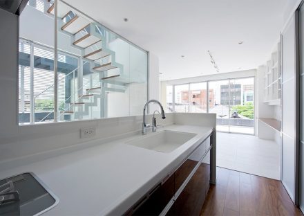 名古屋市千種区の鉄骨造3階建てデザイン注文住宅の完全オーダーメイドの稲妻階段が見えるスタイリッシュなキッチン