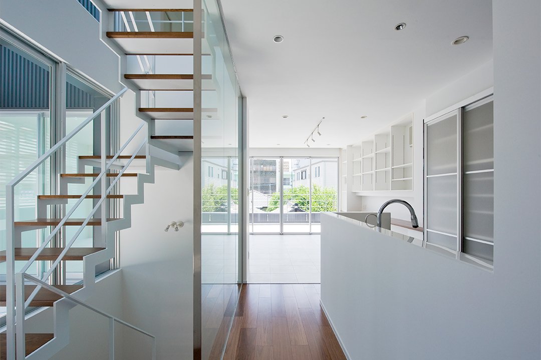 名古屋市千種区の鉄骨造3階建てデザイン注文住宅の透明なスケルトンな稲妻階段と白を基調としたキッチン