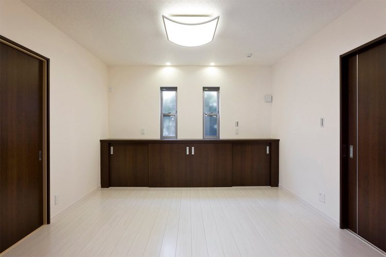 名古屋市東区の注文住宅のダークブラウンの収納棚とドアがアクセントの洋室