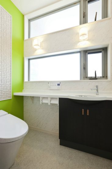 名古屋市千種区の注文住宅の鮮やかな緑がアクセントカラーの手洗い付きのトイレ
