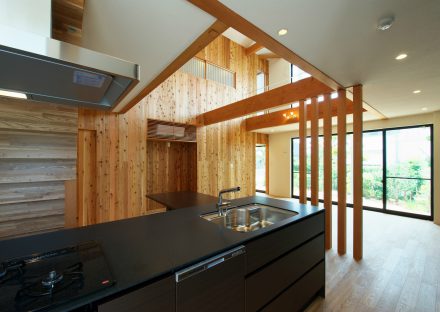 名古屋市守山区の注文住宅の木で囲まれた吹き抜けの下のクールなブラックのアイランドキッチン