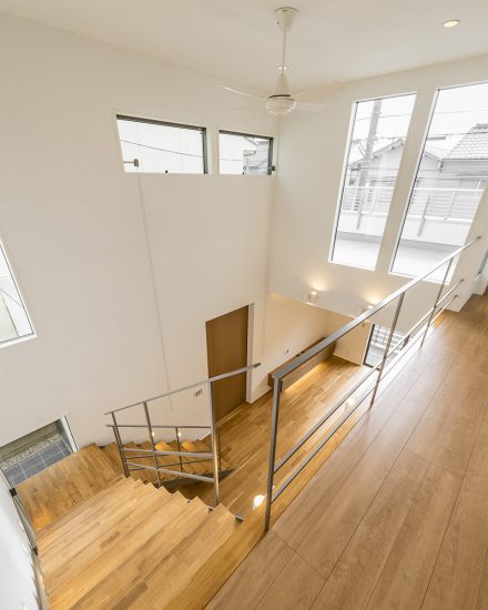 名古屋市北区の注文住宅のシーリングファン付きの光が入る大きな窓がある吹き抜けと明るい階段