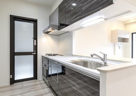 名古屋市昭和区の注文住宅の勝手口が横にあるスタイリッシュなパネルのオープンキッチン