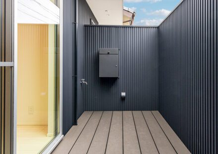 愛知県一宮市のシンプルモダンにこだわった注文住宅のLDKと繋がるプライバシーを確保したモダンなウッドデッキ