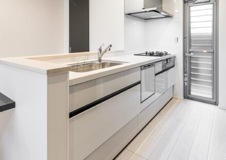 愛知県一宮市のシンプルモダンにこだわった注文住宅の勝手口が横にあり、食洗器も付いた白色のキッチン